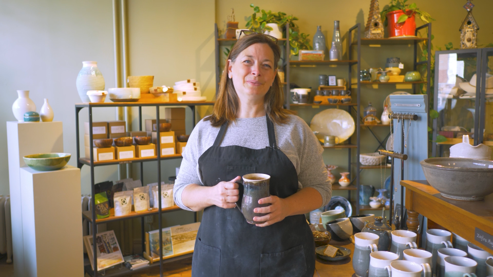 A woman holding a piece of pottery in a pottery store