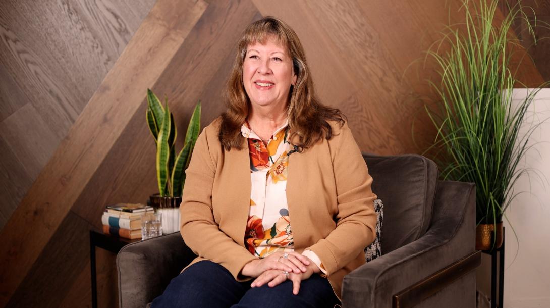 The Chief Executive Officer of Humana sits upright smiling in a chair awaiting to be interviewed.